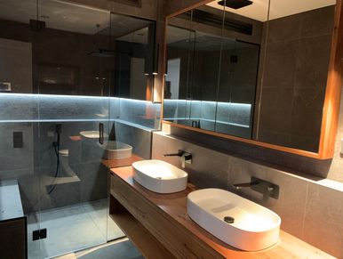 Modern bathroom with double sinks and glass shower enclosure.