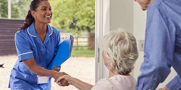 A nurse warmly greeting an elderly woman at her home.