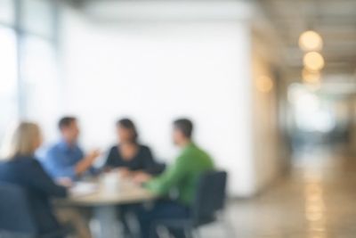 Blurred image of four people having a meeting around a table.
