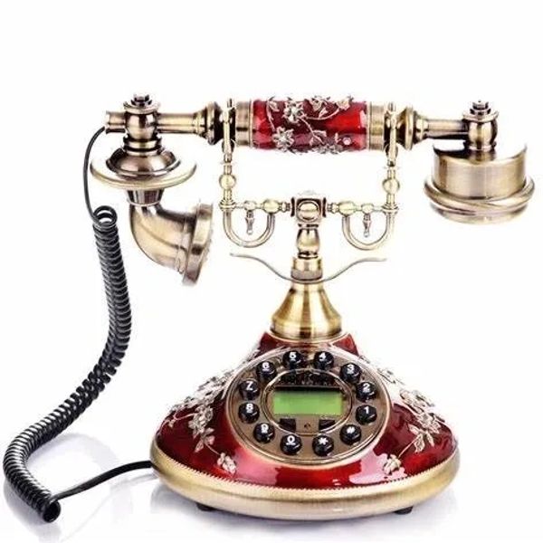 Vintage rotary telephone with ornate red and gold design.