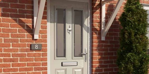 Front door of a brick house with number 8 and a green bush.