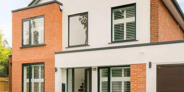 Modern two-story house with brick and white exterior and large windows.