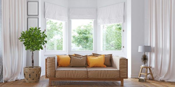Cozy living room with a brown sofa and orange cushions by bright windows.