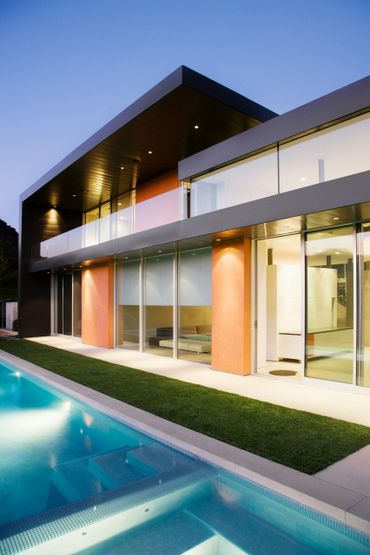 Modern house with large glass windows and a pool at dusk.