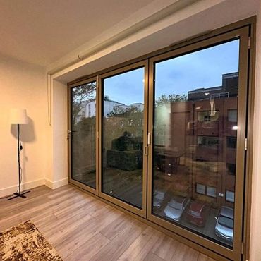 Modern room with large glass sliding doors showing an urban view.