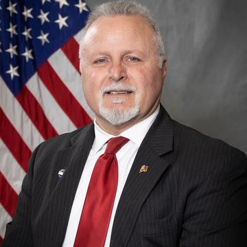 Man in suit with American flag background.
