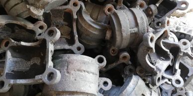 A pile of old, rusty metal mechanical parts with mounting holes.