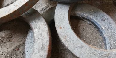 Rusty, weathered metal rings lying on dirt ground.