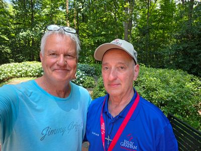Two men smiling in a green outdoor setting.