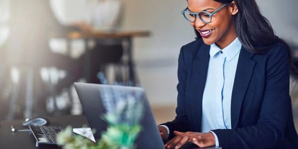 Smiling businesswoman working on laptop in modern office.