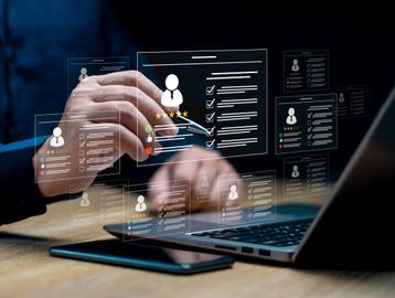 Person interacting with digital HR profiles on a laptop.