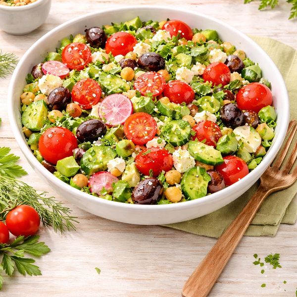 Fresh Mediterranean salad with cherry tomatoes, cucumbers, olives, radishes, chickpeas, and feta cheese.