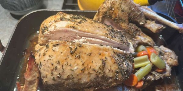 Herb-roasted turkey with vegetables in a roasting pan.