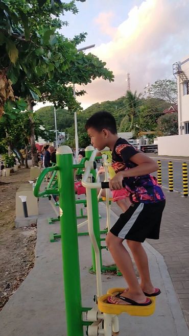 Boy exercising on outdoor equipment.