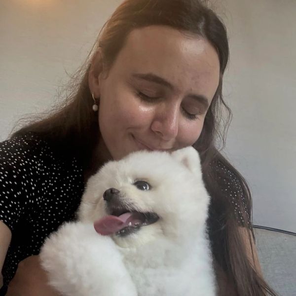 Woman cuddling a fluffy white dog.