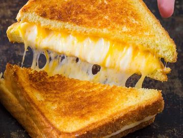 Close-up of a grilled cheese sandwich with melted cheese stretching.