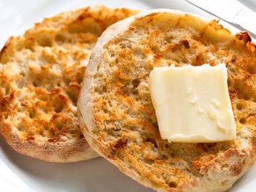 Toasted English muffin halves with a pat of butter on one.