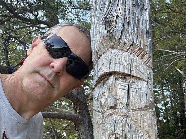 Brent's head leaning against carved tree trunk.