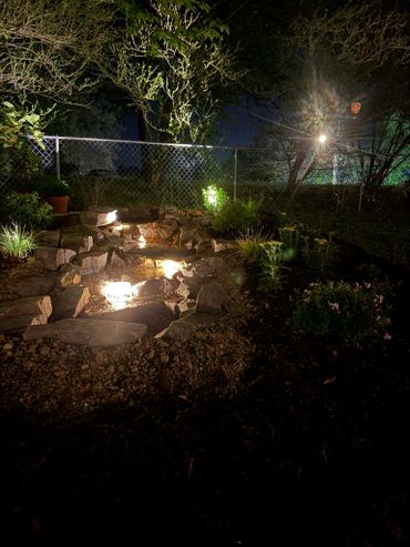 A garden with stone steps illuminated by soft lights at night.