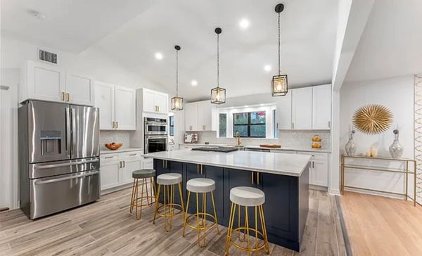Modern kitchen with white cabinets, a large island, and gold-accented stools.