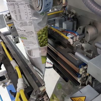 Automated machine packaging green pea snack bags in a factory setting.