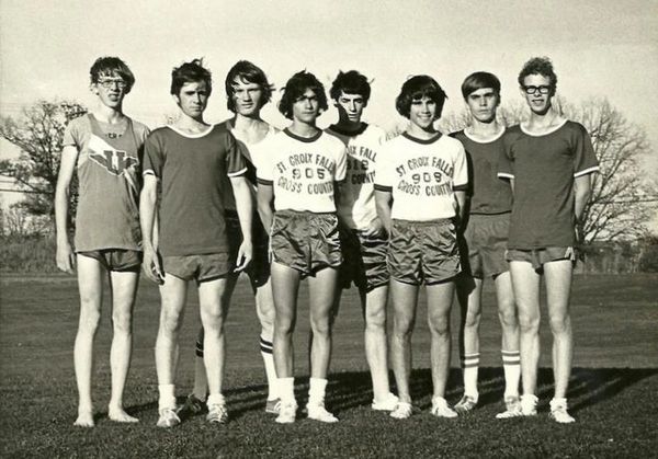 Vintage black-and-white photo of a boys' cross country team standing in a row outdoors.