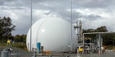 Large spherical industrial storage tank outdoors under cloudy sky.