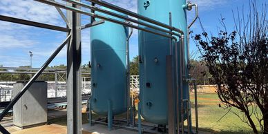 Industrial tanks and pipes outdoors under a clear sky.