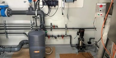 Industrial water filtration system setup with pipes and a tank.
