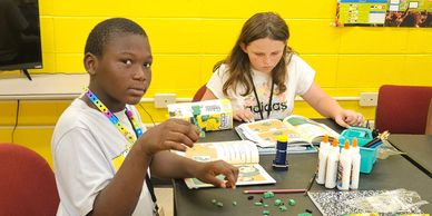 Two children engaged in arts and crafts at a table with supplies.