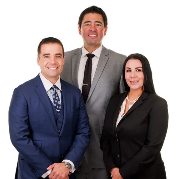 Three professionals in business attire posing confidently against a white background.
