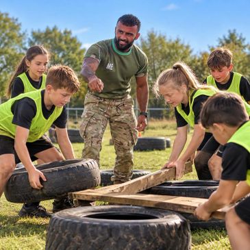 Instructor guiding kids in physical training with tires and wooden planks outdoors.