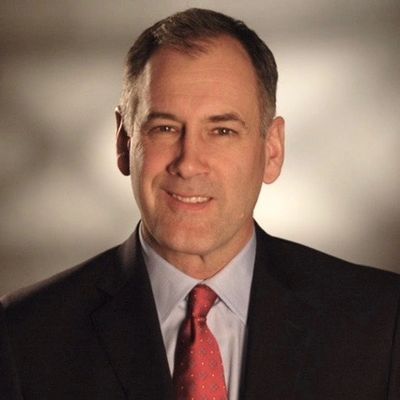 Professional man in suit and red tie smiling at the camera.