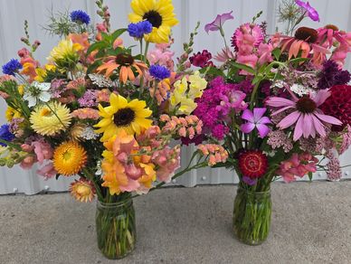 Two vibrant bouquets in glass jars with mixed colorful flowers.