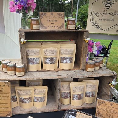 Display of honey caramel products and honey jars at an outdoor market stand.