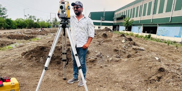 Surveyor using a theodolite on a construction site.