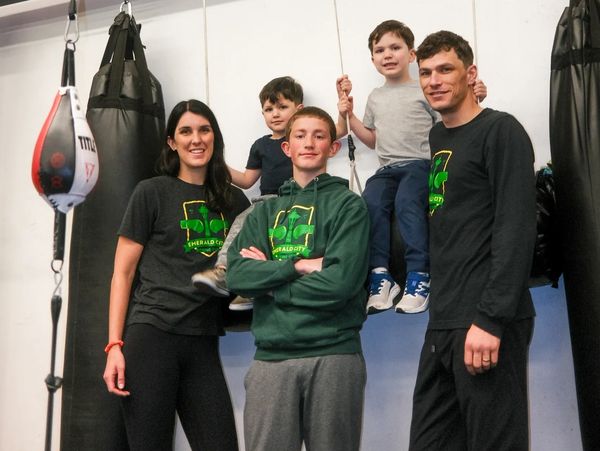 family standing near heavy bags in the boxing gym