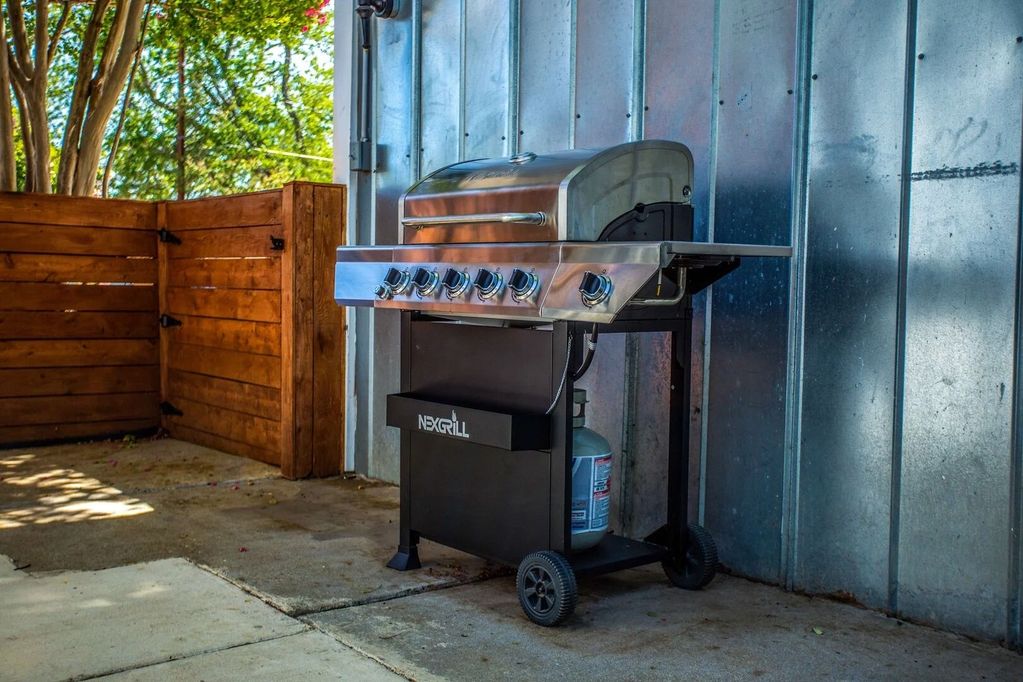 Multi-burner gas grill with propane tanks provided.