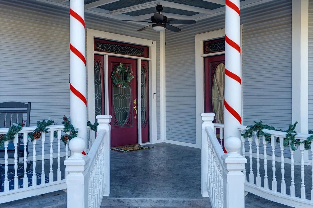 Front porch with Christmas garland and columns wrapped in bright red ribbon