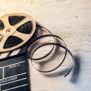 Photo of video real un-spiraling tape above a film clap board on a wooden background.