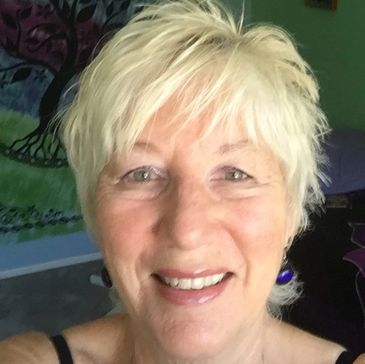 Smiling woman with short blonde hair and green eyes.