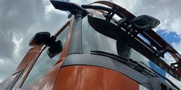 Close-up of a red truck cab against a cloudy sky.