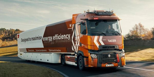 Orange and white energy-efficient truck driving on a curved road.