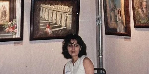 A woman sits in a gallery surrounded by classical-style paintings on the wall.
