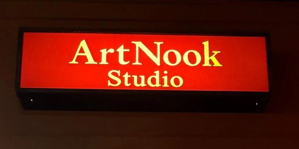 Illuminated red sign reading 'ArtNook Studio' on a dark background.