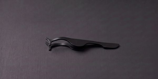 Black metal tool with a curved design on a dark surface.