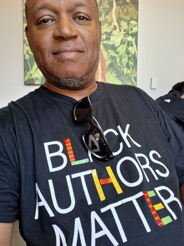 Man wearing a Black Authors Matter t-shirt with colorful letters and sunglasses.