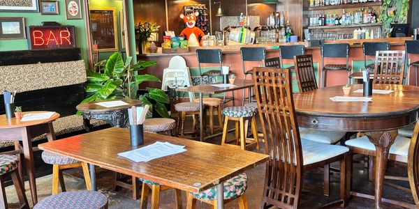 Cozy bar interior with wooden tables, chairs, and vibrant decor.