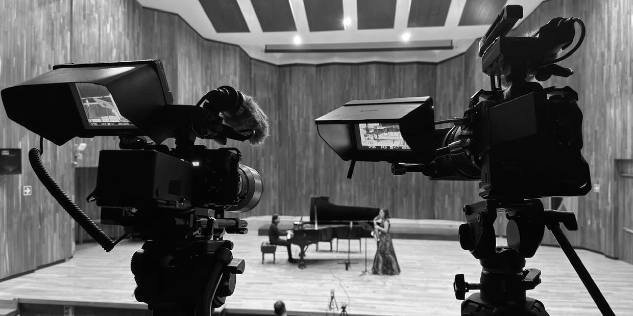 Cámaras grabando una actuación musical en un auditorio.