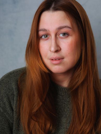 Portrait of a woman with long red hair and green sweater.